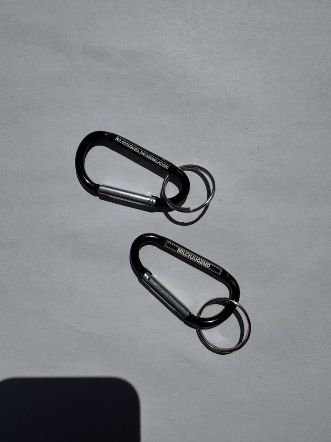 Karabiner Gravur «No apologies. No assimiliation.» auf Vorderseite und Gravur «Milchjugend» auf Rückseite