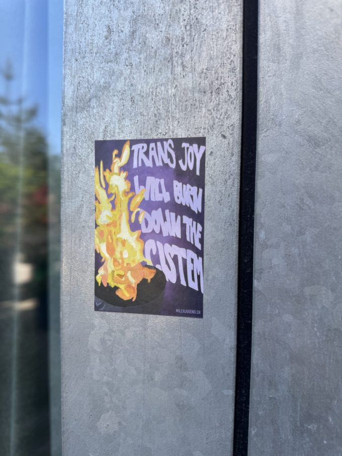 Sticker mit Zeichnung einer gelben Flamme und handschriftlichem Slogan «Trans joy will burn down the Cistem» und klein gedruckt «milchjugend.ch»